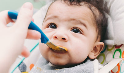 baby being spoon fed by mother's hand