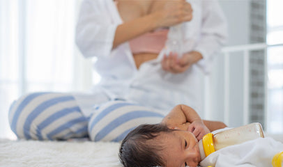 woman pumping breast milk while baby is feeding