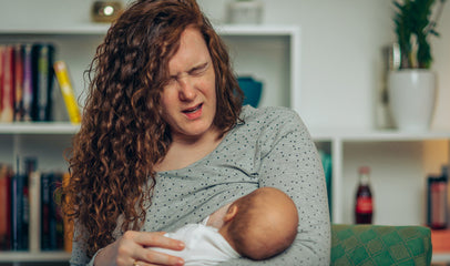 woman wincing in pain from breastfeeding