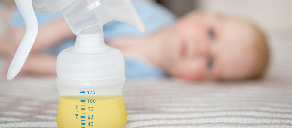 baby looking at bottle of colostrum