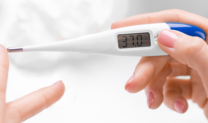 woman holding digital basal thermometer