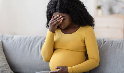 frustrated pregnant black woman sitting on couch