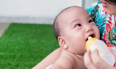 woman feeding baby bottle of milk