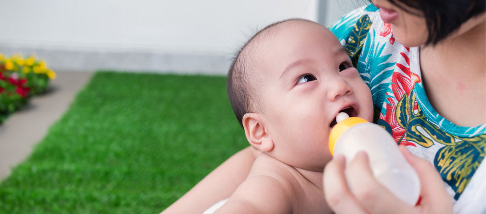 woman feeding baby bottle of milk