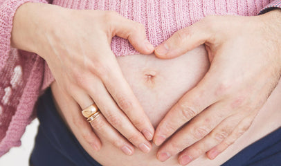 woman making a heart sign on pregnant belly