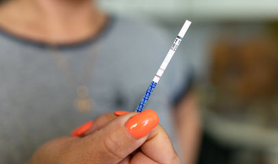 woman holding pregnancy test strip