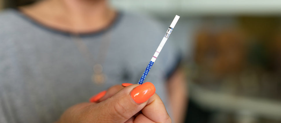 woman holding pregnancy test strip