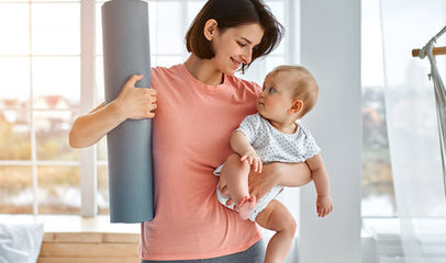 woman holding a yoga mat and baby