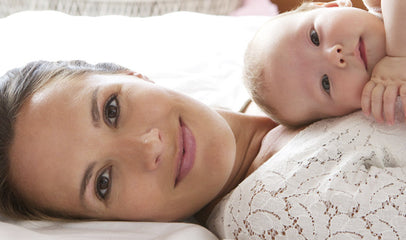 woman laying on bed with baby on chest