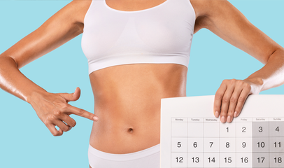 woman holding calendar pointing to stomach