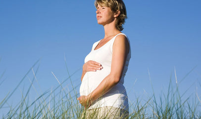 pregnant woman in grassy field getting vitamin D from the sun