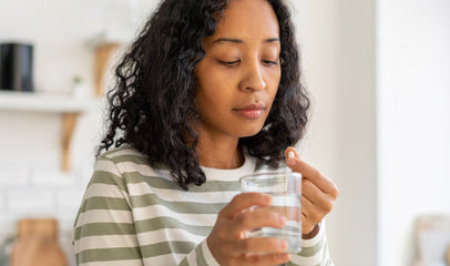 woman taking prenatal vitamin with water