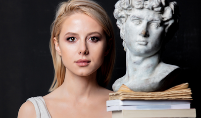 woman next to greek statue and books